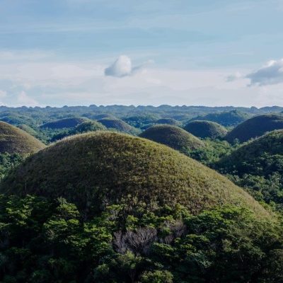 An aerial beautiful landscape of Chocolate Hills in Cebu Philippines under a blue sky